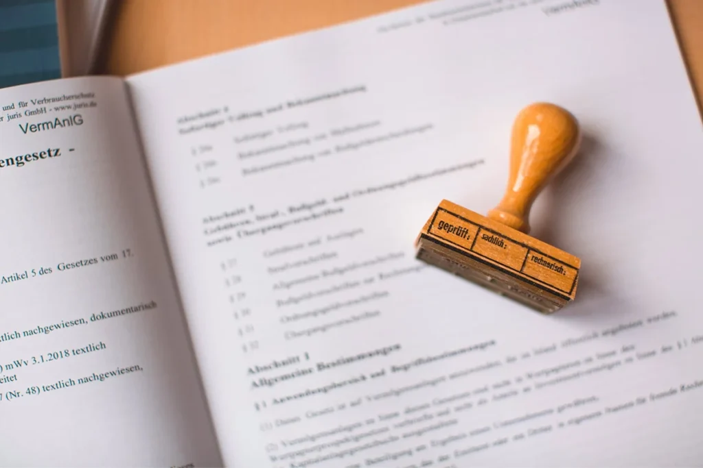 A rubber stamp rests on an open legal document, signifying the official approval, regulations, and compliance requirements in the legal field.